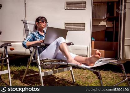 Family vacation travel, holiday trip in motorhome. Woman looking at the laptop near the camping . Caravan car Vacation. Family vacation travel, holiday trip in motorhome RV. Wi-fi connection information communication technology.