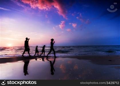 Family walk on the beach at sunset