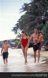 Family Walking Along Beach And Smiling