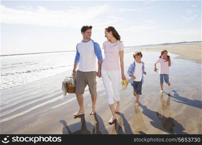 Family Walking Along Beach With Picnic Basket