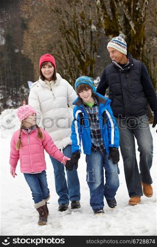 Family Walking Along Snowy Street In Ski Resort