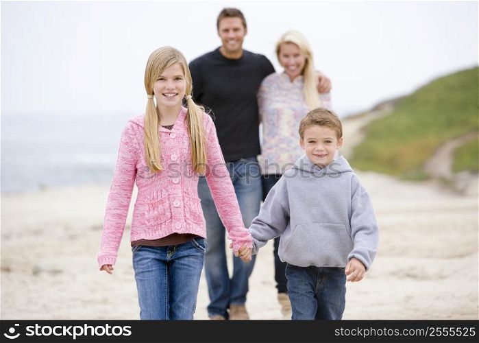 Family walking at beach holding hands smiling