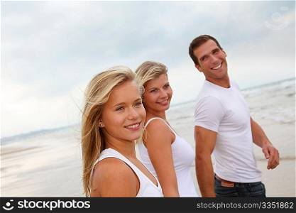 Family walking hand to hand on a sandy beach
