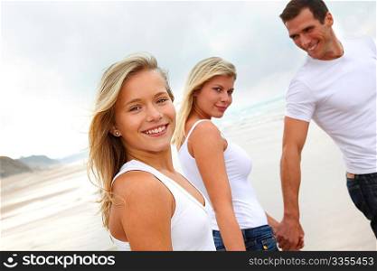 Family walking hand to hand on a sandy beach