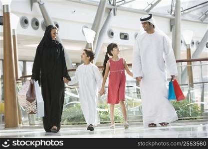 Family walking in mall holding hands and smiling (selective focus)