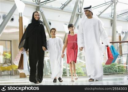 Family walking in mall holding hands and smiling (selective focus)