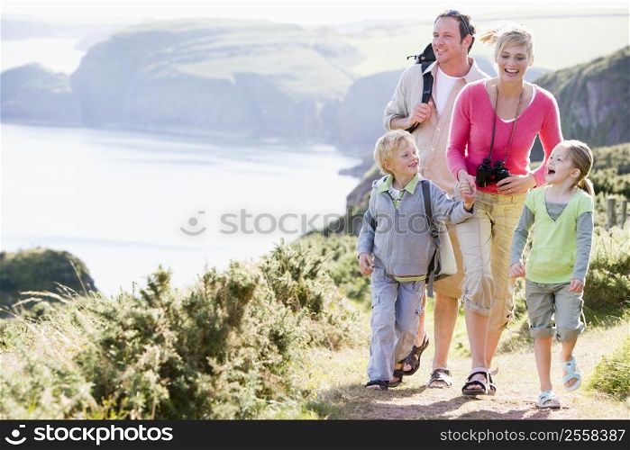 Family walking on cliffside path holding hands and smiling