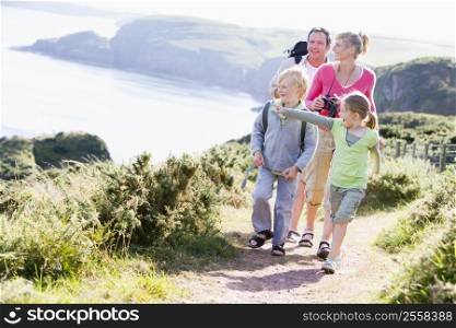 Family walking on cliffside path pointing and smiling