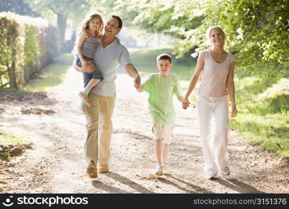 Family walking outdoors holding hands and smiling