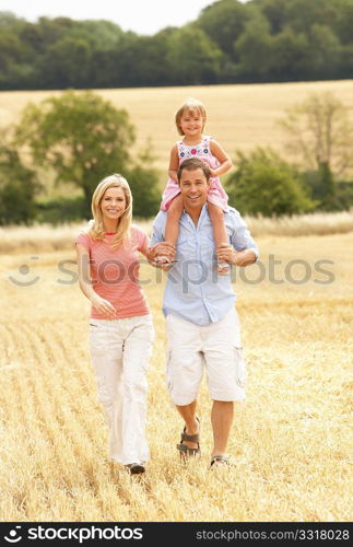 Family Walking Together Through Summer Harvested Field