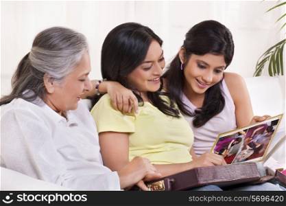 Family watching photo album at home and smiling