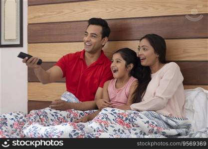 Family watching television together in bed