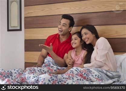 Family watching television together in bed