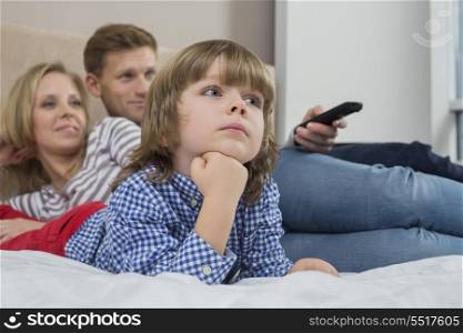 Family watching TV in bedroom