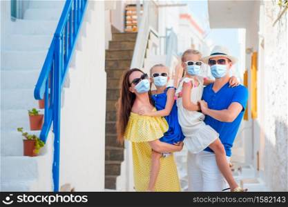 Family wearing masks for prevent virus summer vacation on Mykonos. Family having fun outdoors on Mykonos streets