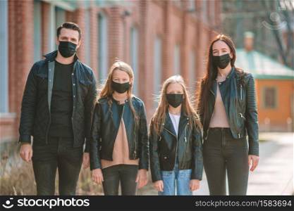 Family wearing protective medical mask for prevent virus Covid-19. Parents and kids wearing a surgical mask.. Family wearing a mask on a background of a modern building,