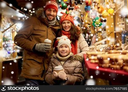 family, winter holidays and celebration concept - happy mother, father and little daughter with takeaway drinks at christmas market on town hall square in tallinn, estonia over snow. family with takeaway drinks at christmas market