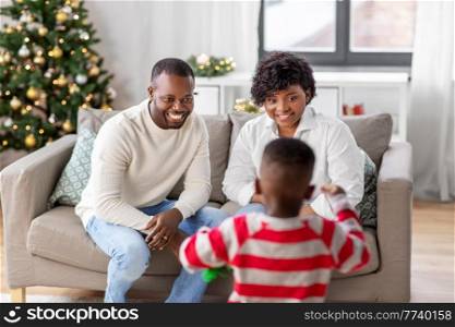 family, winter holidays and people concept - happy african american mother, father and baby son at home on christmas. happy african american family on christmas at home