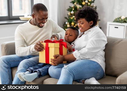 family, winter holidays and people concept - happy african american mother, father and baby son opening gift box at home on christmas. african family opening christmas gift at home