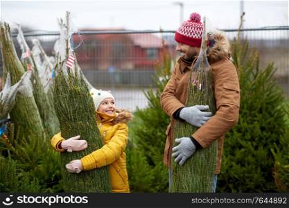 family, winter holidays and people concept - happy father and little daughter buying christmas tree at street market. happy family buying christmas tree at market