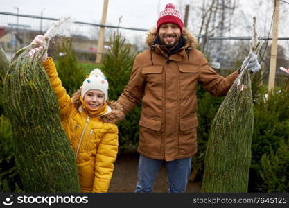 family, winter holidays and people concept - happy father and little daughter buying christmas tree at street market. happy family buying christmas tree at market