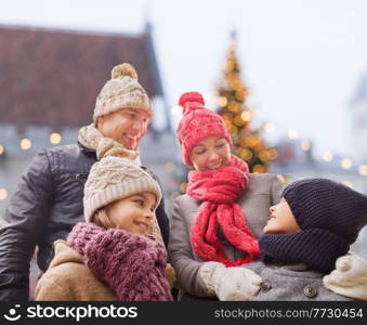 family, winter holidays and people concept - happy mother, father, son and daughter outdoors over christmas tree on background. happy family with children on christmas outdoors