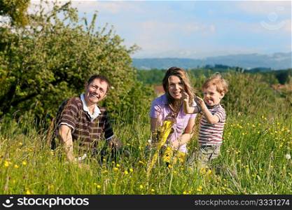 Family with a little boy playing in the grass on a summer meadow