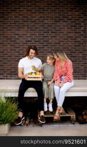 Family with a mother, father and daughter sitting outside on steps of a front porch of a brick house