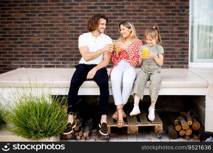 Family with a mother, father and daughter sitting outside on steps of a front porch of a brick house