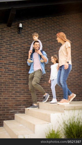 Family with a mother, father, son and daughter walking by the wall of a brick house