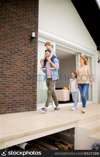 Family with a mother, father, son and daughter walking by the wall of a brick house