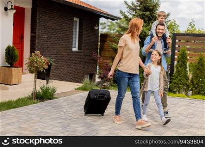 Family with a mother, father, son and daughter walking with  abaggage outside on the front porch of a brick house