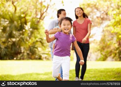 Family With Baby In Carrier Walking Through Park