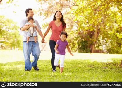 Family With Baby In Carrier Walking Through Park