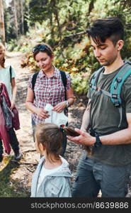 Family with backpacks hiking in a mountains actively spending summer vacation together walking down a forest path. Active people spending time outdoors in a forest. Family with backpacks hiking in a mountains actively spending summer vacation together