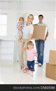 Family with box moving into new home smiling