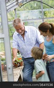 Family with boy planting flowers in greenhouse