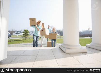 Family with cardboard boxes entering into new house