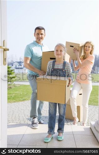 Family with cardboard boxes entering new house