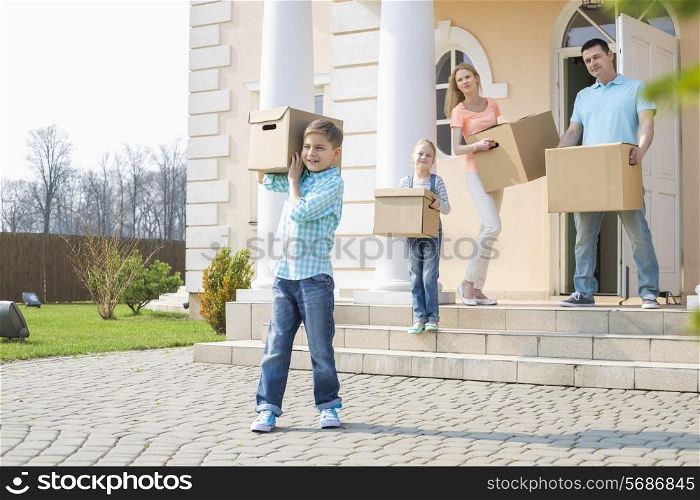 Family with cardboard boxes moving out from house
