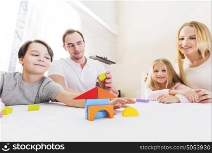 Family with children constructing house. Family of four people with children constructing house of toy blocks, real estate concept