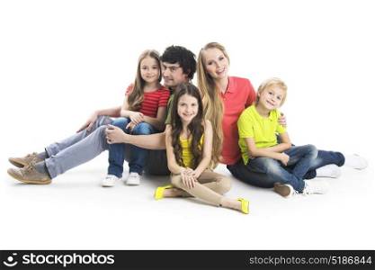 Family with children. Happy smiling family of two parents and three children sitting on the floor studio isolated on white background