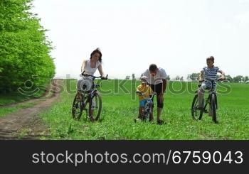 Family with children having a weekend excursion on their bikes. Father helping child learn to ride a bike