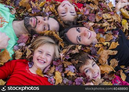 Family with heads together, lying in autumn leaves