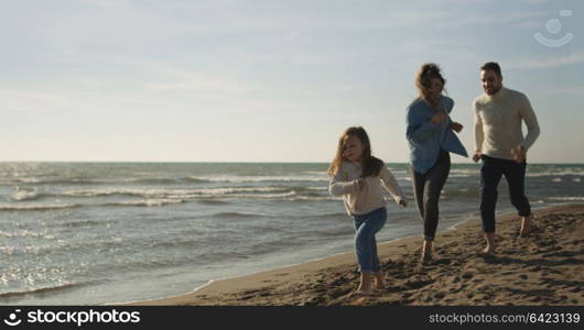 Family with kids resting and having fun at beach during autumn day