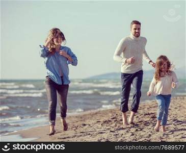 Family with kids resting and having fun at beach during autumn day filter
