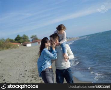 Family with little daughter resting and having fun at beach during autumn day. Young happy family enjoying vecation during autumn day