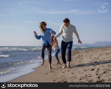 Family with little daughter resting and having fun at beach during autumn day. Young family enjoying vecation during autumn day