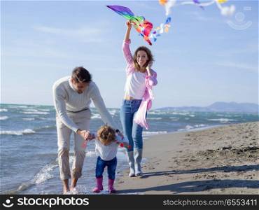 Family with little daughter resting and having fun with a kite at beach during autumn day. happy family enjoying vecation during autumn day