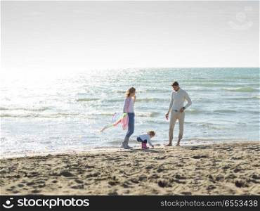 Family with little daughter resting and having fun with a kite at beach during autumn day. happy family enjoying vecation during autumn day